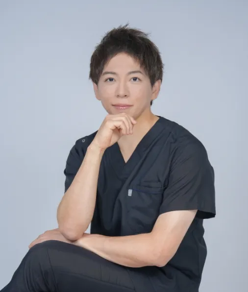 紺色のスクラブを着た院長 平田侑が頬に手を当てたポーズの写真
