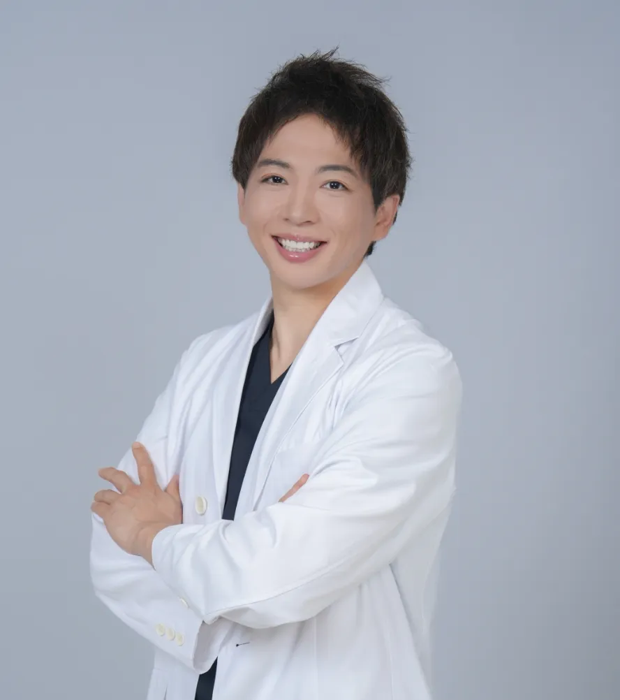 白衣を着た院長 平田侑が腕を組み笑顔でこちらを向いている写真